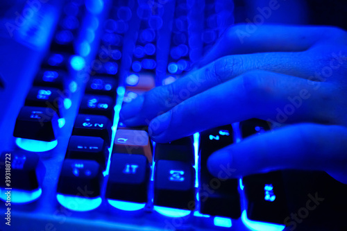 Multifunction keyboard with set of red button. WASD keys are used in many video games. Close-up on human hands on a neon lit keyboard, actively pushing buttons, playing games Online.