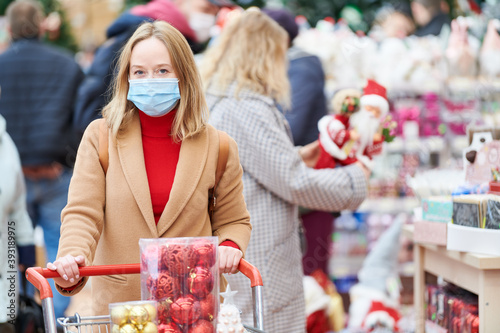 woman in mask buying new year decoration in shop at coronavirus lockdown. photo