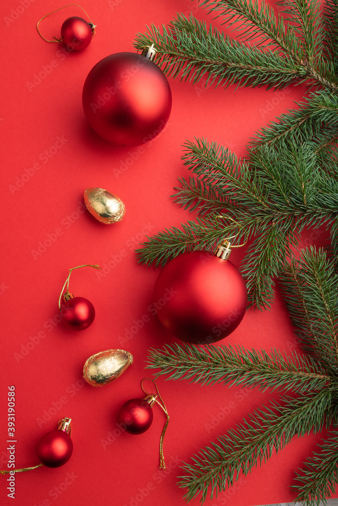 Christmas or New Year composition. Decorations, red balls, fir and spruce branches, on a red background. Top view.