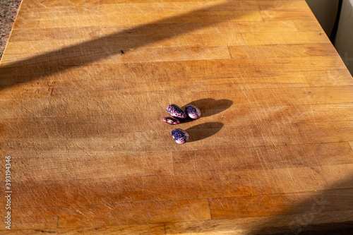 A few fresh heirloom scarlet runner beans on a light wooden cutting board