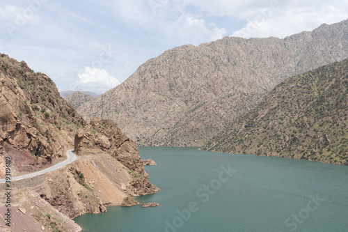Mountain gorge with a reservoir and winding road along steep rocky slopes under a clear sky in Iran.