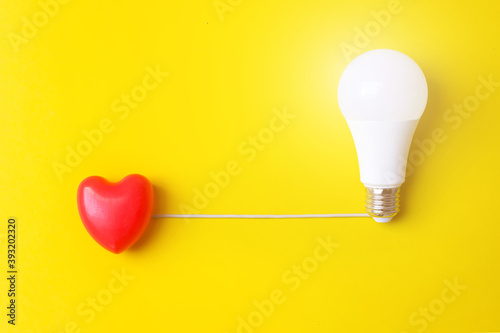 Glowing bulb and red heart on yellow background, uniqueness concept. Idea, innovation, creativity concept, design template, copy space photo