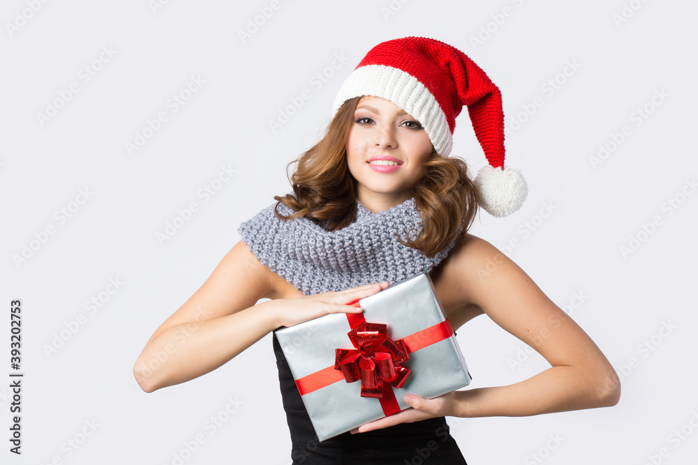 Happy young woman with santa hat holding a Christmas present on a white. Happy young woman with santa hat holding a Christmas present on a white.