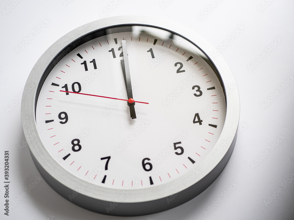 Close up of a ticking clock on white background, pointing a few minutes past midnight, copyspace, window reflection Close up of a ticking clock on white background, pointing a few minutes past midnight, copyspace, window reflection