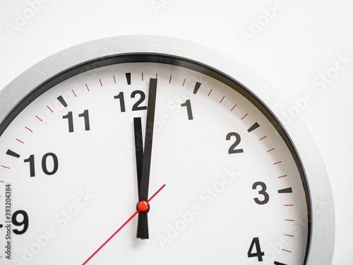Close up of a ticking clock on white background, pointing a few minutes past midnight, copyspace