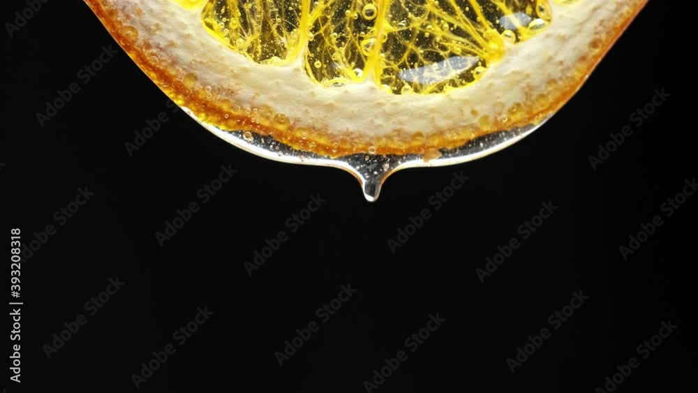 Macro Texture shot of Honey dripping down a fresh lemon slice on white. Freshness, citrus and flu remedy concepts.
