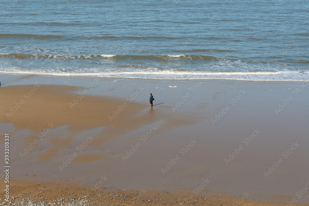 Seagulls on the beach, East England North Sea sandy beach view with a mans walking on the shore in distance, seagulls flying over, photo taken from the top