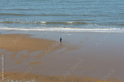 Seagulls on the beach, East England North Sea sandy beach view with a mans walking on the shore in distance, seagulls flying over, photo taken from the top