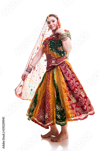 Beautiful young female Bollywood dancer in traditional vivid orange dress with veil