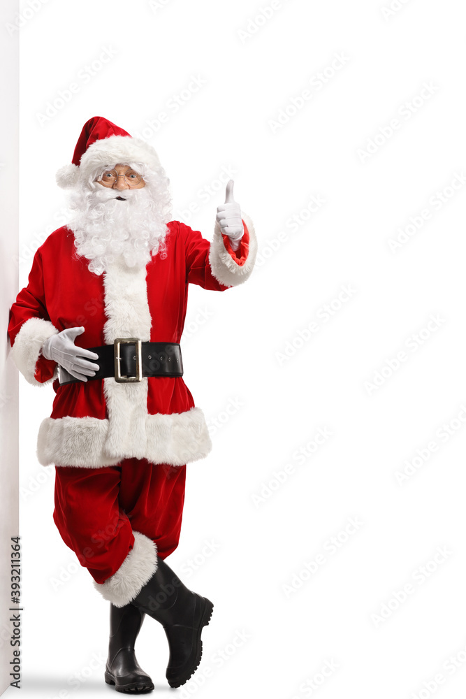 Santa claus leaning on a wall and gesturing a thumb up sign Santa claus leaning on a wall and gesturing a thumb up sign