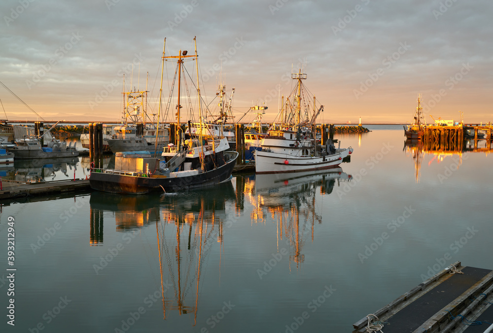 Steveston Fishboats at Dawn. Calm water and clouds over the harbor of Steveston, British Columbia, Canada near Vancouver. Steveston is a small fishing village on the banks of the Fraser River.

