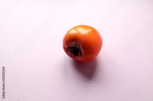 One ripe persimmon fruit on a pastel background, close-up, side view, space for text © MARYIA