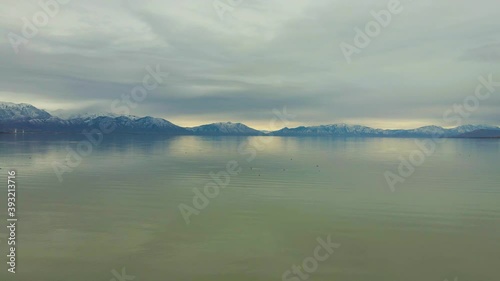 Wallpaper Mural Flying above a seemingly endlessly large lake with seagulls below on the water and snowy mountains in the distance Torontodigital.ca