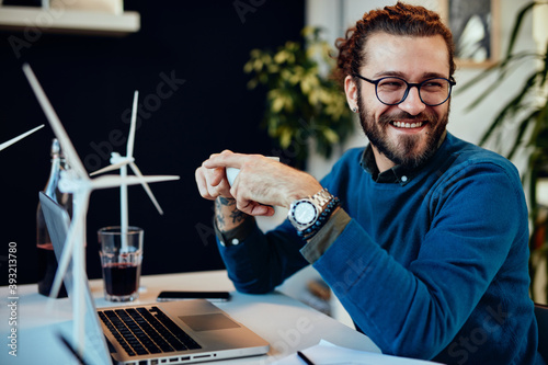 Smiling attractive engineer sitting in his office and drinking coffee on a break. Sustainable development concept. photo