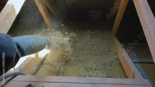 Medium shot of thermal insulation of house with mineral wool in granules. Man making thermal roof insulation layer