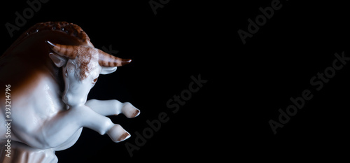 Ceramic figurine of powerful bull on black background. Bull symbol of the year 2021.With copy space