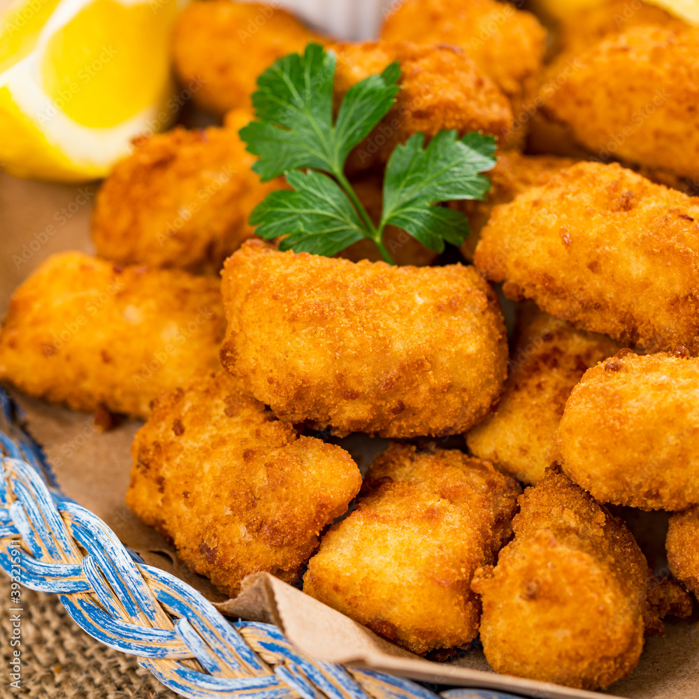 Crispy Fish Bites Snack Size. Deep Fried Pollock Fish Fingers with Tartar Dipping Sauce on a Wooden Board. Selective focus.