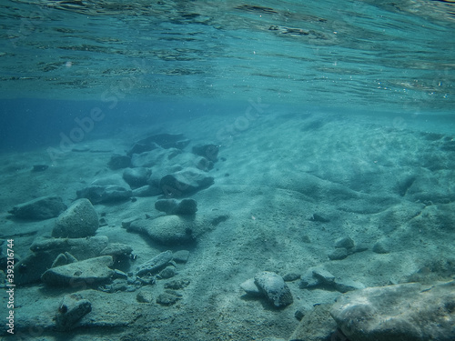 Billede på lærred Underwater background with stony seabed, clear teal water and ocean surface