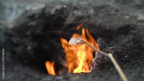 Long wooden stick with delicious marshmallow roasting over mystical Turkey landmark of bright flames burning on Chimaera mountain hillside close view.