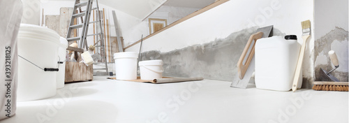 Low angle of indoor shot of construction or building site of home renovation with tools on white floor with paint buckets and primer jerry can