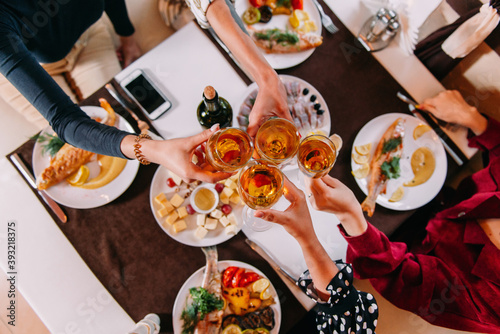 Glasses with wine close-up in female hands at a table in a restaurant resting girlfriends in the evening on a weekend after work