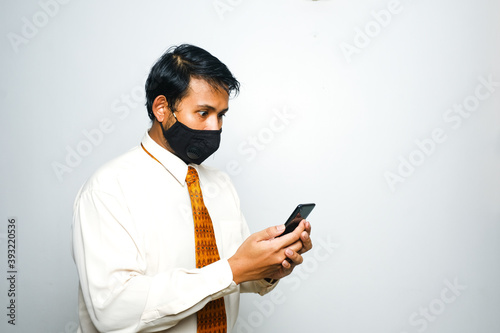A picture of men wearing mask looking at his smartphone and surprise after looking at Malaysia Covid-19 case.