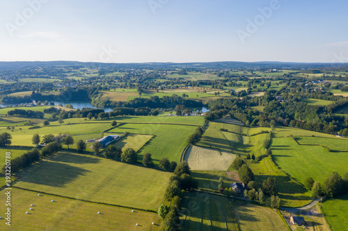 Expansive drone view over the countryside surrounding Waimes in the Belgian Ardennes, June 2020, showing green fields, hedgerows and rural farms stretching into the distance under a bright summer sky.