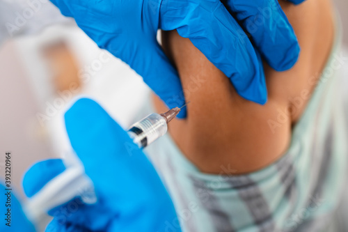 Close up shot of doctor s hand giving shot or vaccine to a patient s shoulder. Vaccination and prevention against flu or virus pandemic. Coronavirus or Covid-19 healthcare concept.