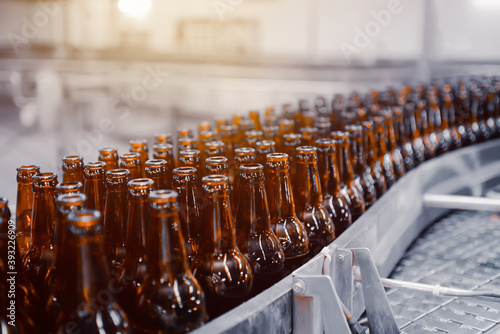 Glass beer bottles of brown color on the conveyor line of beer bottling close up
