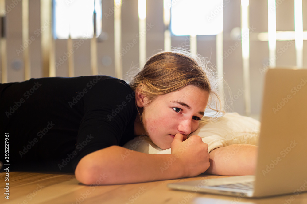 teenage girl lying on wooden floor looking at laptop teenage girl lying on wooden floor looking at laptop