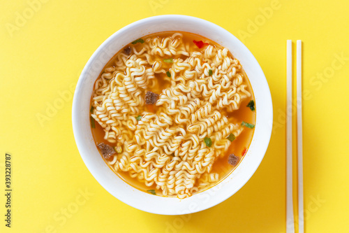 Photos Instant noodle soup in a white bowl on yellow background top view