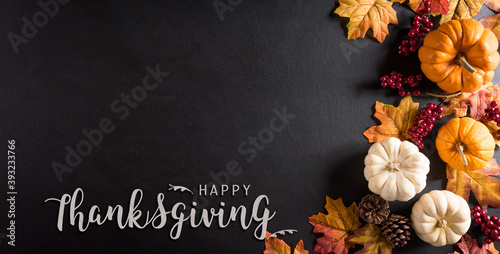 Thanksgiving background decoration from dry leaves,red berries and pumpkin on blackboard background. Flat lay, top view for Autumn, fall, Thanksgiving concept.
