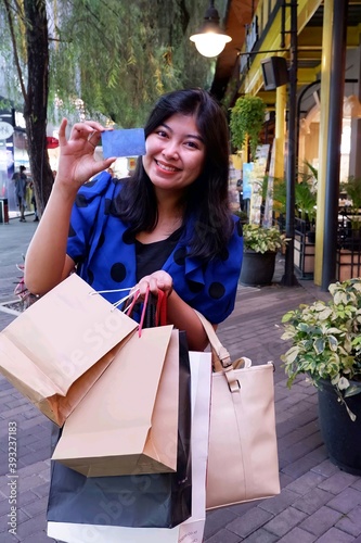 beautiful asian woman a is shopping for a lot of goods at a mall using a credit card copy of space