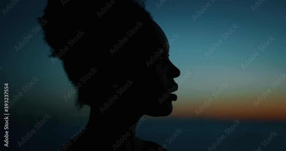 Cinematic close up silhouette of young african woman is happy to enjoy a summer vacation on a beach with a sea on a sunset. Cinematic close up silhouette of young african woman is happy to enjoy a summer vacation on a beach with a sea on a sunset.