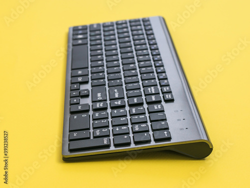 Modern wireless keyboard on a yellow background.