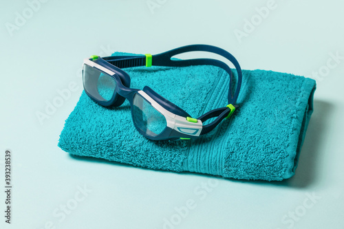 Swimming glasses on a blue towel on a blue background.