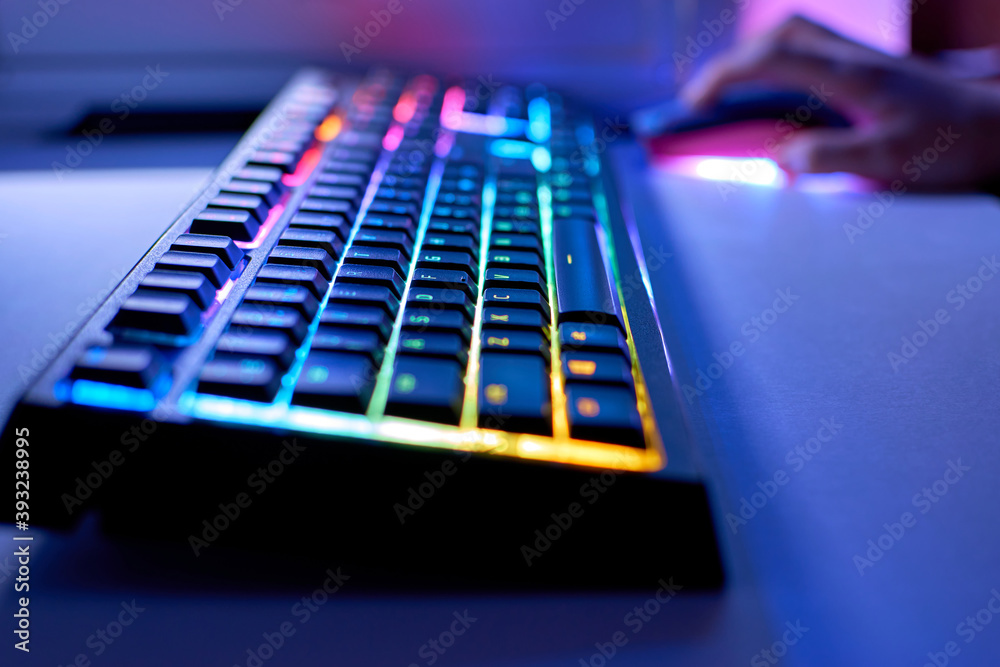 Backlit keyboard and mouse in the background. Gaming concept. Gaming led keyboard with multi-colored backlight, blurry background.