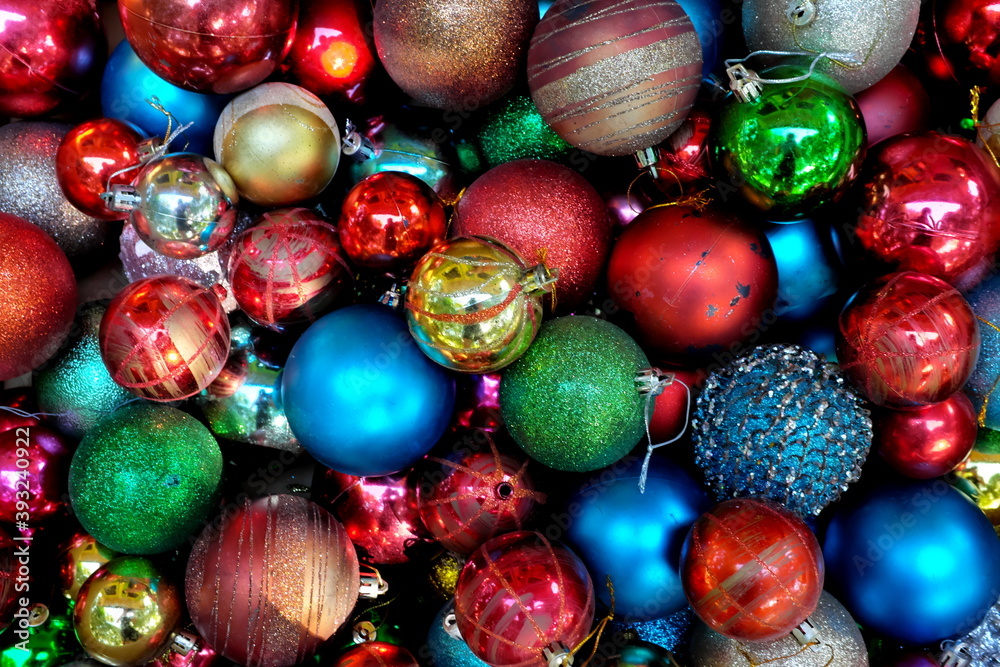 Top view of pile of dark and colorful Christmas balls for an abstract holiday season background backdrop pattern. 