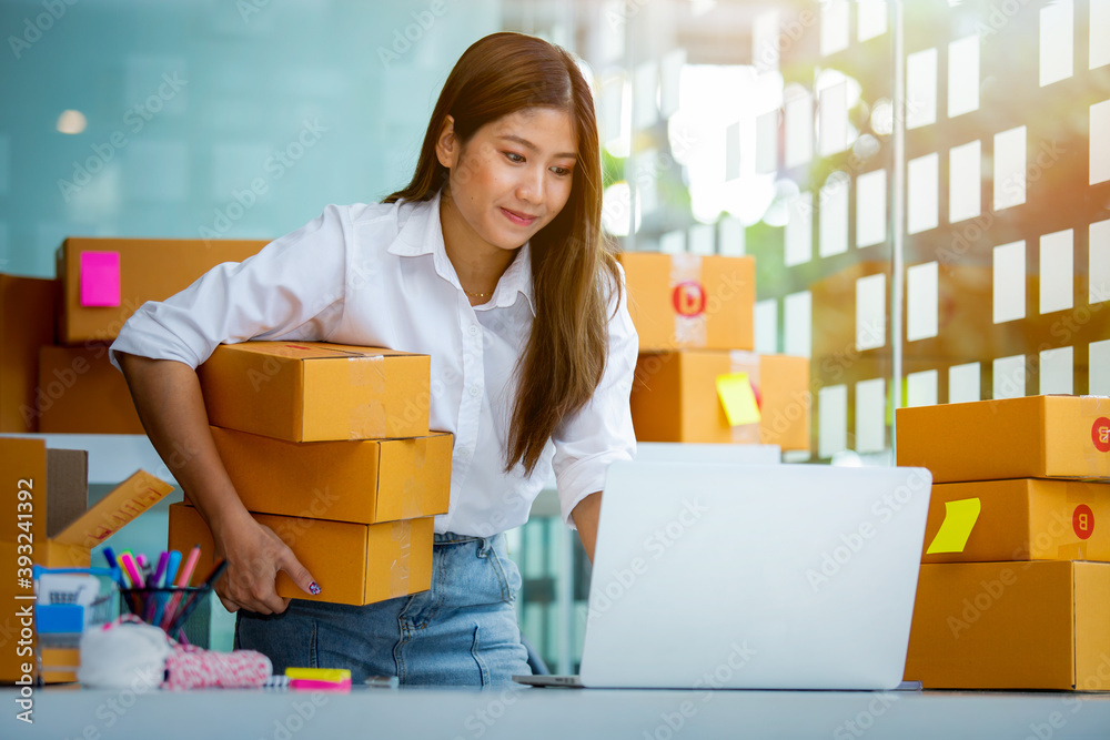Starting Small business entrepreneur SME freelance,Portrait young woman working at home office, BOX,smartphone,laptop, online, marketing, packaging, delivery, SME, e-commerce concept. Starting Small business entrepreneur SME freelance,Portrait young woman working at home office, BOX,smartphone,laptop, online, marketing, packaging, delivery, SME, e-commerce concept.