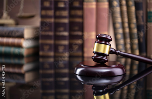 Law theme. Judge chamber. Judge’s gavel and collection of legal books on the brown desk and the brown background.