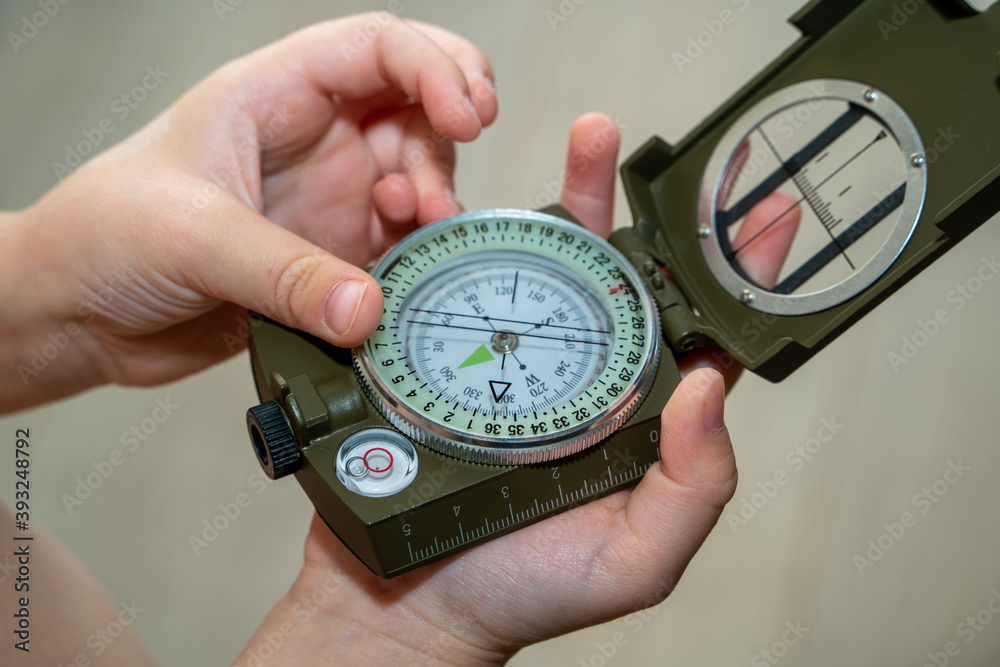 Children's hands holding a compass. A little boy holds a green compass in his hands. Learn orienteering. Childhood curiosity and adventure Children's hands holding a compass. A little boy holds a green compass in his hands. Learn orienteering. Childhood curiosity and adventure