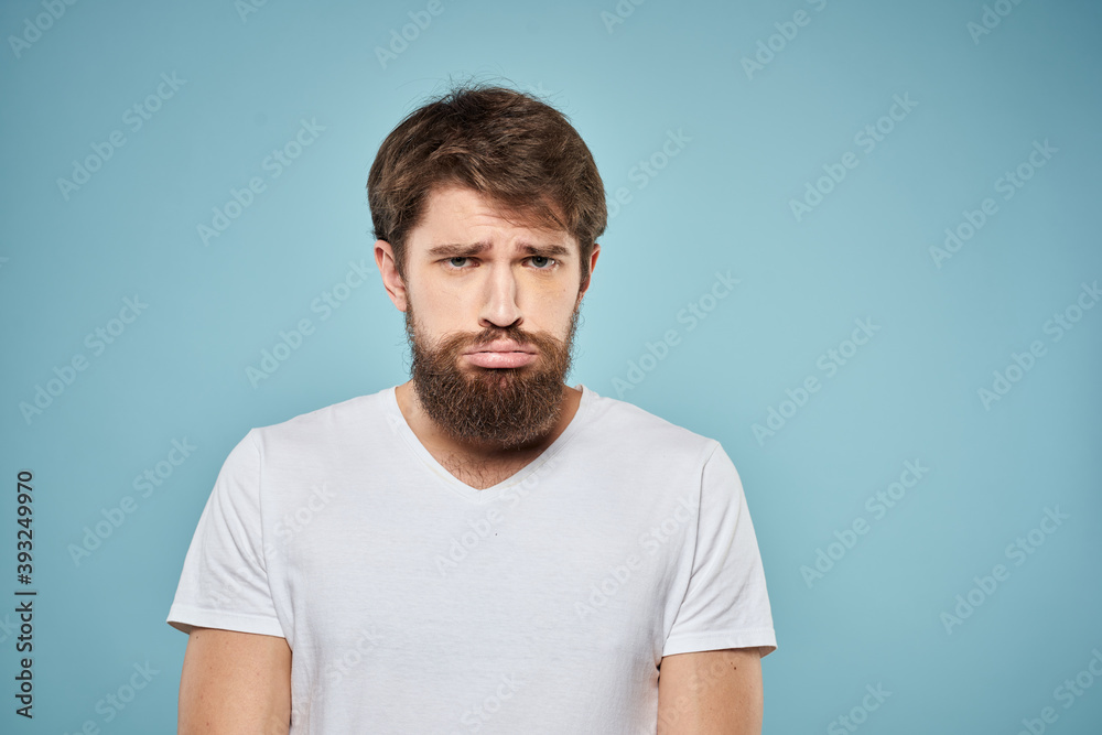 Obraz premium Man in white t-shirt lifestyle studio emotions facial expression blue isolated background