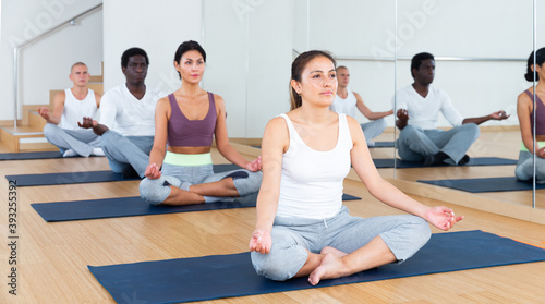 Group of man and woman making yoga meditation in lotus pose at gym