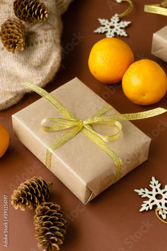 Christmas gift box wrapped in craft paper with golden bow on a brown background