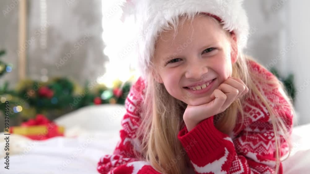 4k Portrait Christmas girl. Smiling child in Santa Claus hat looking into the camera at home 4k Portrait Christmas girl. Smiling child in Santa Claus hat looking into the camera at home