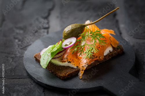 Canvas Print Salmon open sandwich on Pumpernickel bread with vegetables, herbs and soft chees