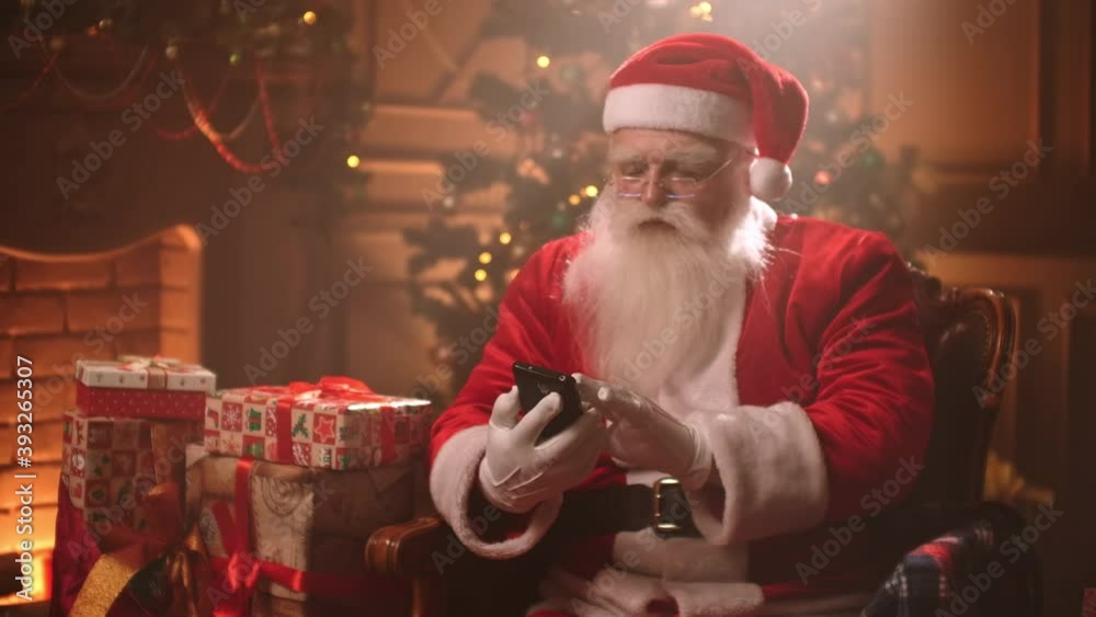 old Santa Claus is typing message by smartphone, sitting alone in his room at Christmas, wizard is using gadget old Santa Claus is typing message by smartphone, sitting alone in his room at Christmas, wizard is using gadget