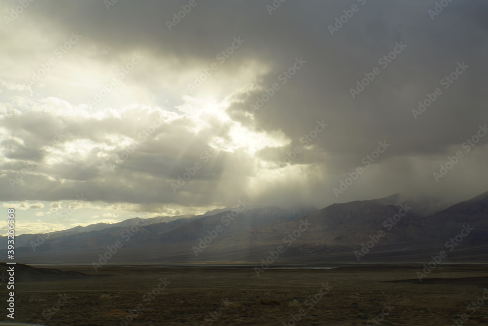 Moody landscape view of sun beams and rays breaking through storm clouds over Death Valley Moody landscape view of sun beams and rays breaking through storm clouds over Death Valley