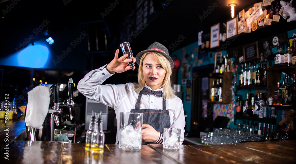 Girl bartender mixes a cocktail in the beerhall