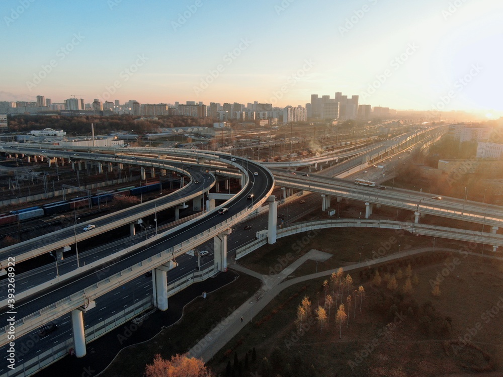 Fototapeta premium Aerial view panorama of multi-level transport interchange in the center of the big city at dawn. Beautiful panoramic landscape infrastructure of modern city from great height